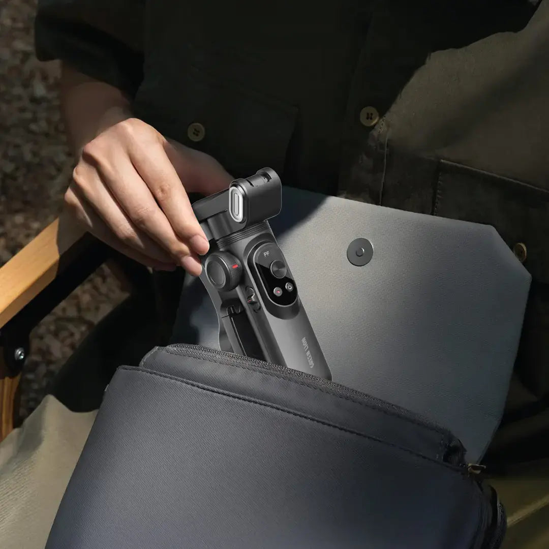 Person holding a camera stabilizer over a backpack outdoors