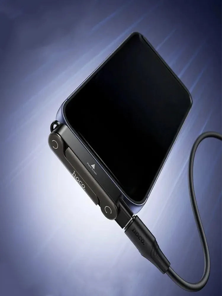 Hoco UA47 2-in-1 charging adapter and phone stand plugged into a smartphone, propping it up as a kickstand while connected to a charging cable, available at Lebtech Store with fast delivery across Lebanon.
