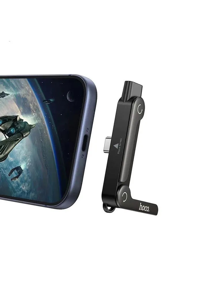 Hoco UA47 2-in-1 adapter standing vertically with its kickstand leg extended next to an iPhone, demonstrating how the male interface plugs into the phone port, from Lebtech Store Lebanon.
