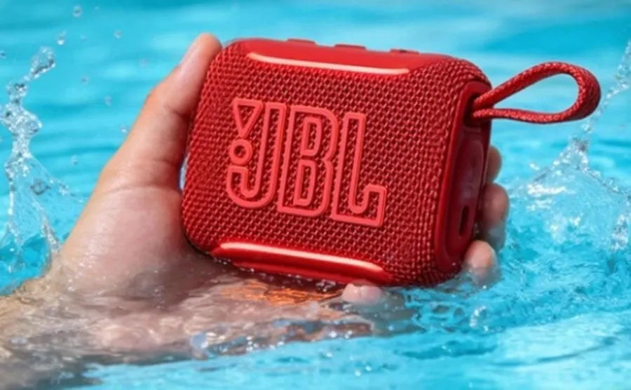 Red JBL Go 5 AirTouch waterproof speaker being held over water, available at LecTech Store Lebanon, showcasing its IP68 fully submersible and pool-ready design