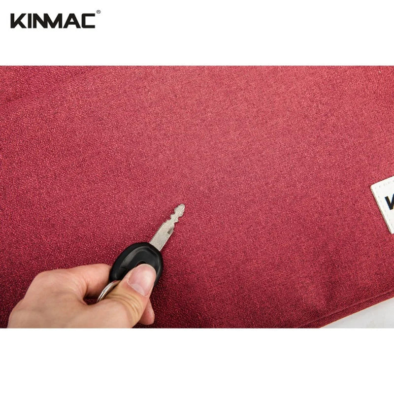 Hand holding a key over a red surface with 'KINMAC' branding.