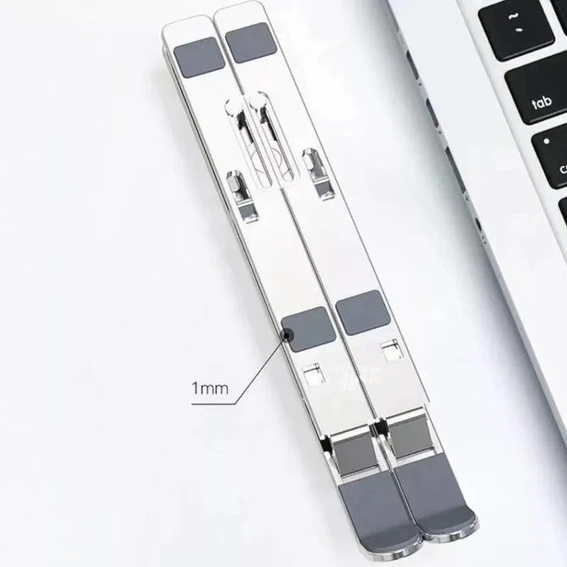 Mikuso LS-060 laptop stand folded beside a laptop, showing silicone pads and retaining hooks
