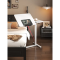 Multi-function height-adjustable white desk used as a bedside table from LebTech Store Lebanon, showing a tilted surface for a tablet and an ergonomic sit-stand design with fast delivery across Lebanon.