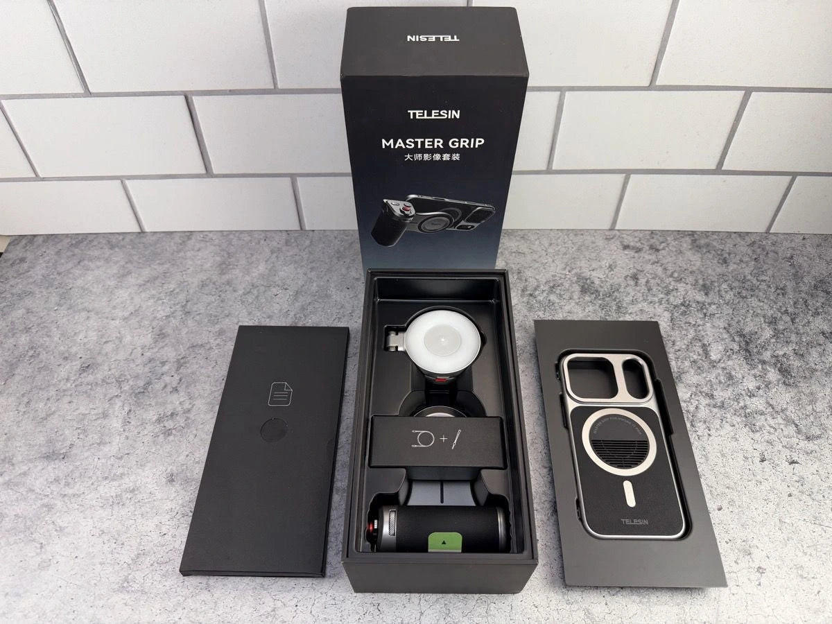 Unboxing of the TELESIN Master Grip filmmaking kit showing the black retail box alongside the unboxed handle, magnetic fill light, and protective phone case inside the packaging trays, from Lebtech Store Lebanon.